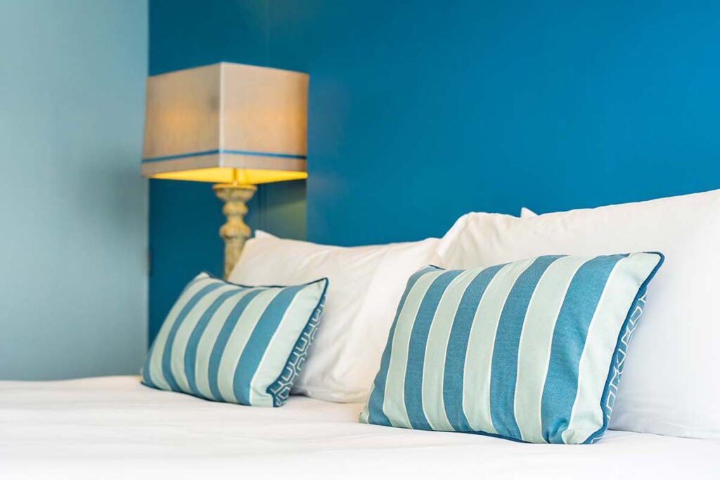 Quarto decorado em cor azul com almofadas listradas, referência ao novembro azul