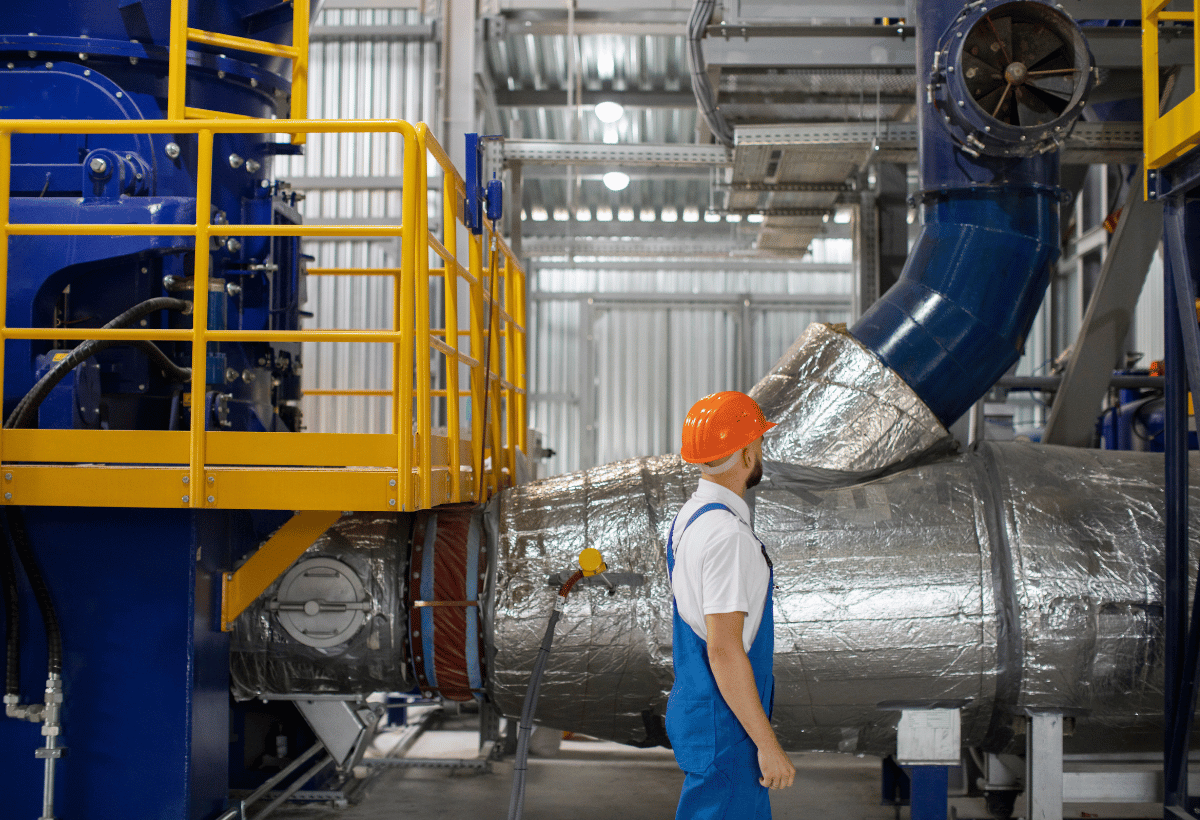 Profissional em ambiente industrial com tubulações e equipamentos identificados por cores de segurança